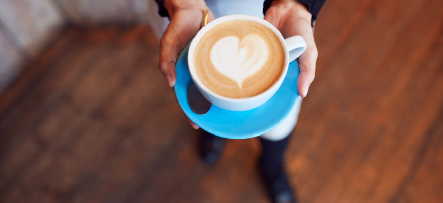 Close,Up,Of,Waitress,In,Coffee,Shop,Holding,Cup,With